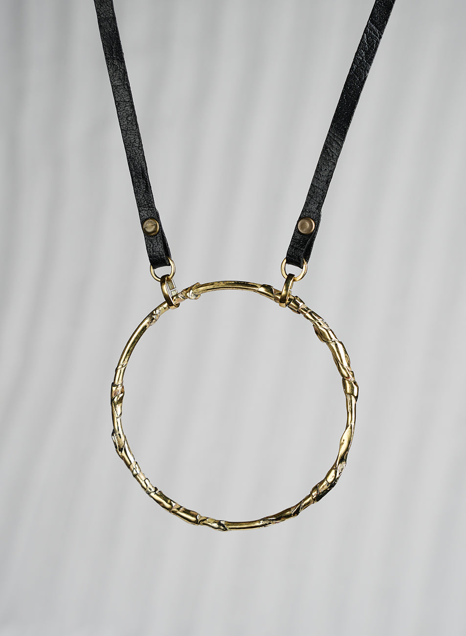Short necklace featuring a powerful circle symbol, handcrafted metalwork with a leather cord.