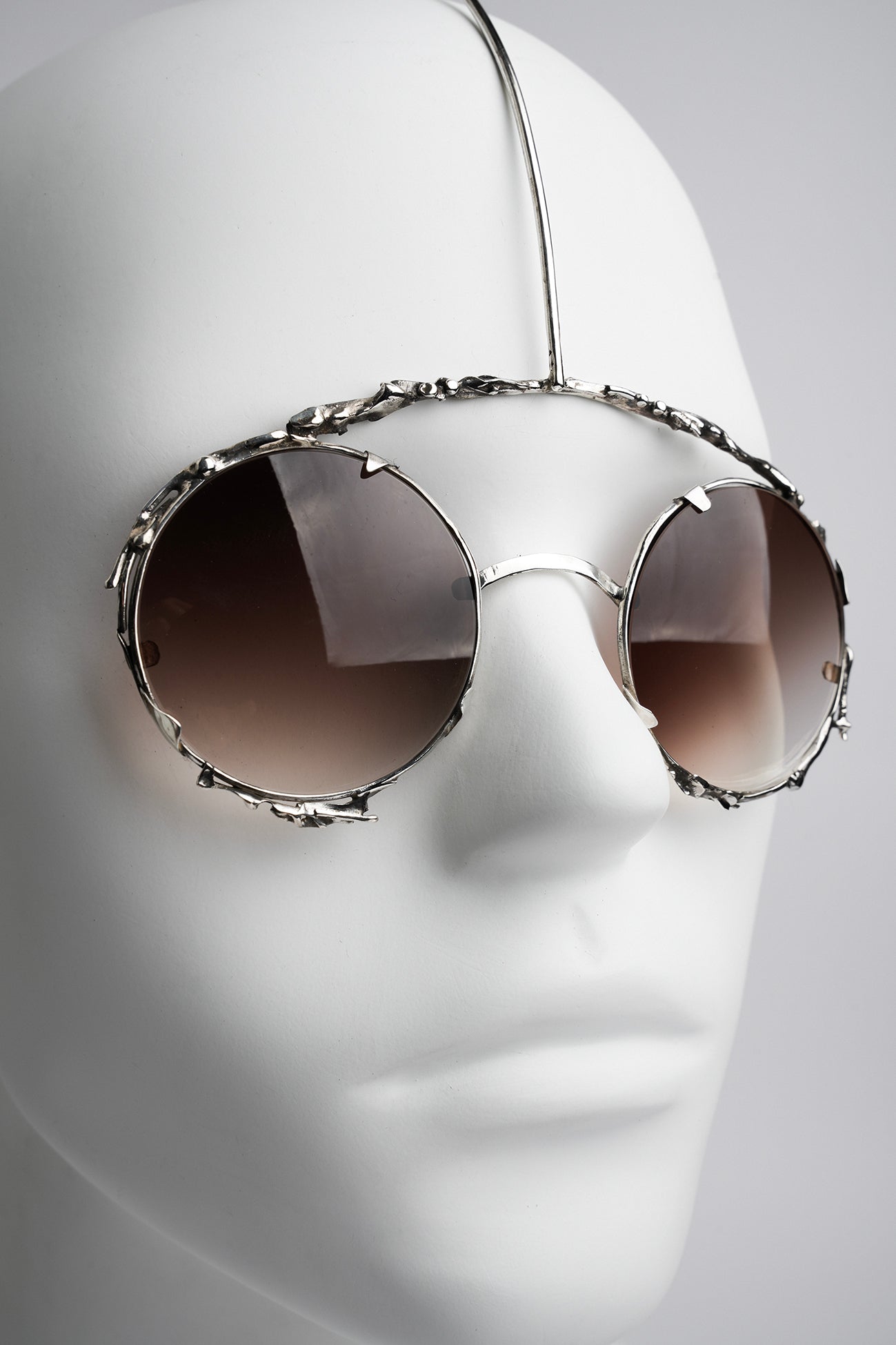 futuristic type of sanglasses worn like a piece of jewelry in silver