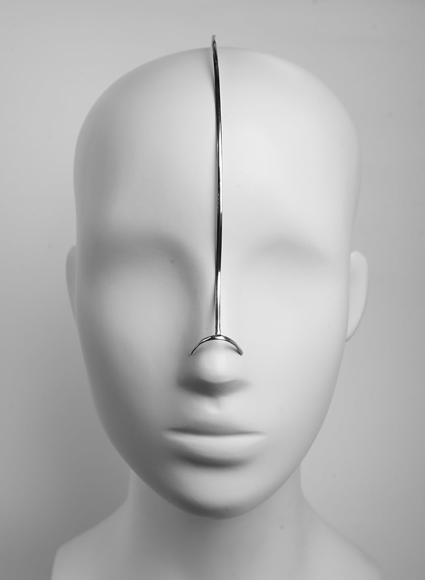 face adornment by a minimalist silver piece that follows the contours of the face 