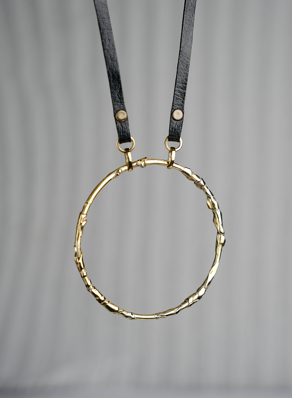 leather necklace with a large circular sculpted pendant golden color
