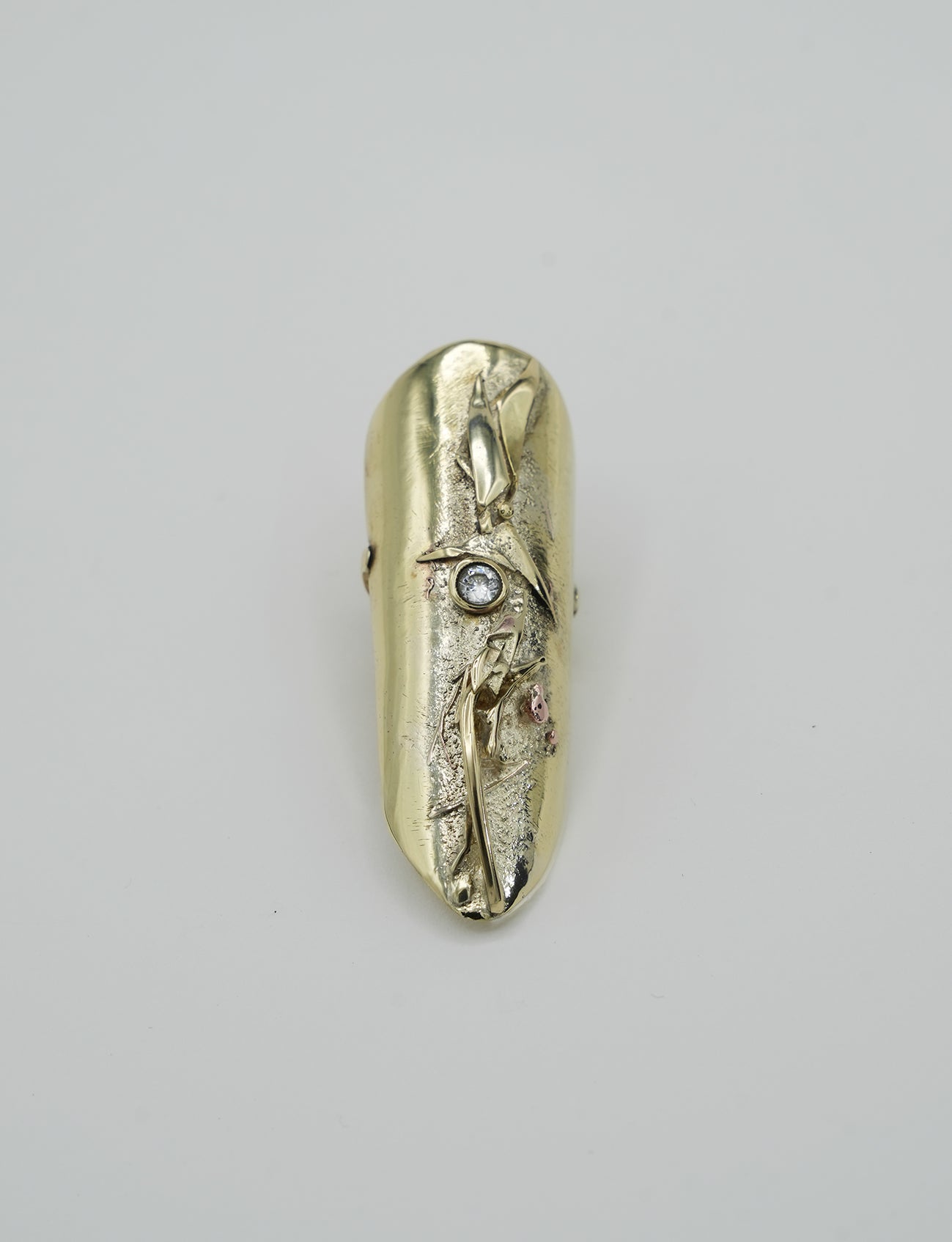Sculptural brass ring in organic raw design with textured relief, crystal and natural gold finish.