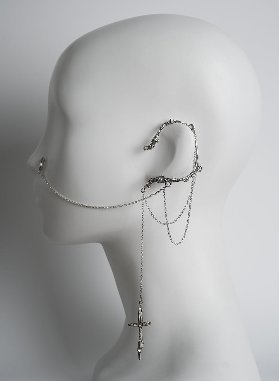 ear cuff in silver, with chains ending on a nose clip and a cross pendant