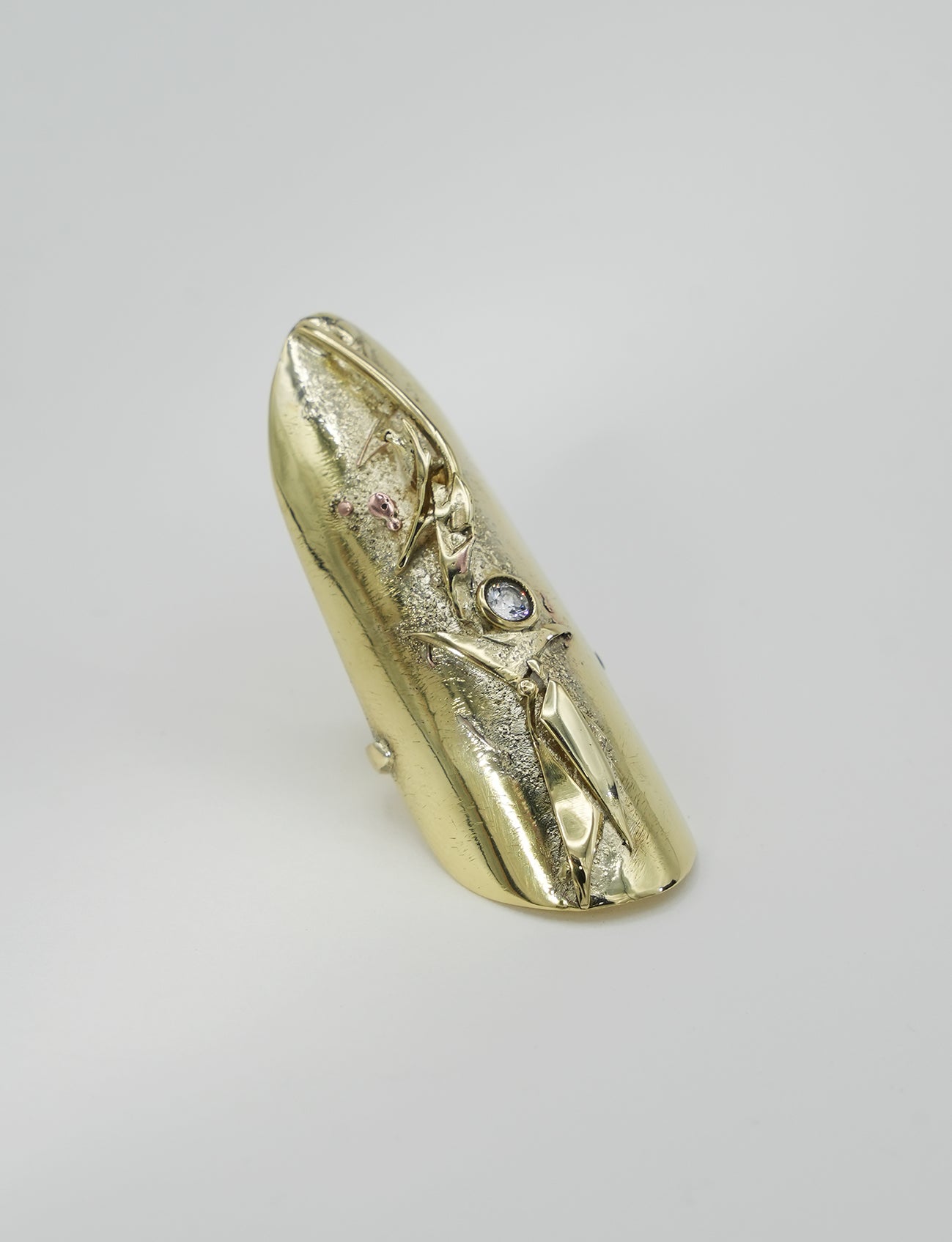 Sculptural brass ring in organic raw design with textured relief and natural gold finish.